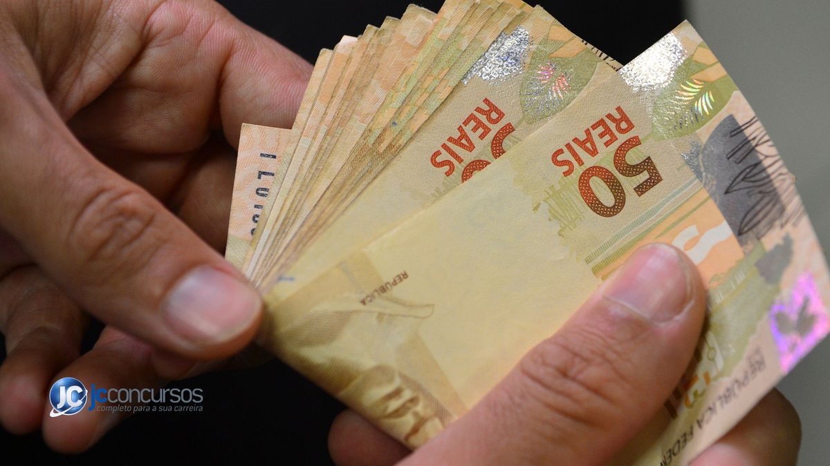 Um homem segura notas de dinheiro - Agência Brasil - Auxílio de R$ 710