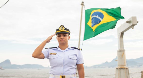 Concurso Marinha: com bandeira do Brasil ao fundo, militar presta continência - Divulgação