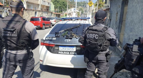 Concurso da PC RJ: policiais vistos de costas ao lado de viatura - Divulgação