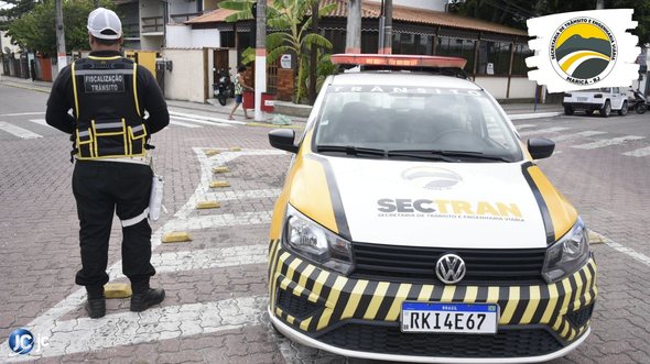 Concurso da Sectran de Maricá RJ: agente municipal de trânsito de costas, ao lado de veículo - Divulgação