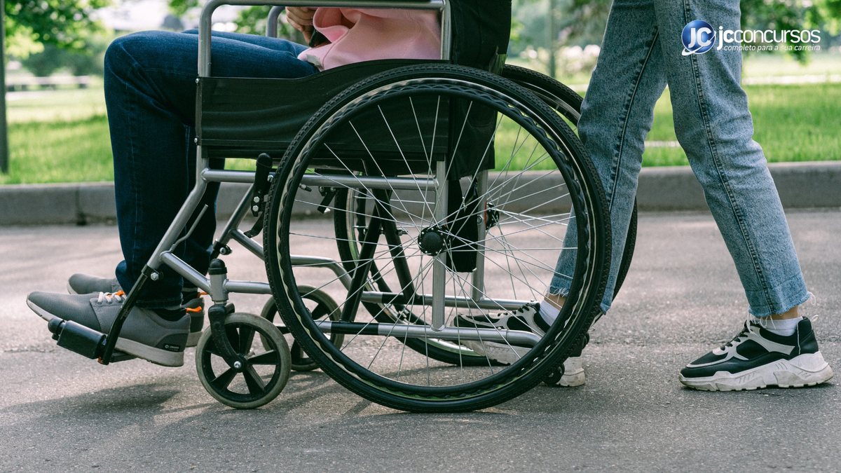 Um homem empurra uma cadeira de rodas - Divulgação JC Concursos - Crédito Caixa