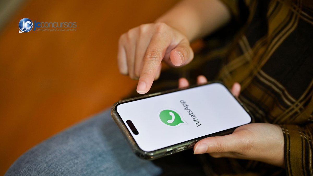 Uma mulher segura um telefone aberto com o aplicativo de mensagem - Canva - WhatsApp